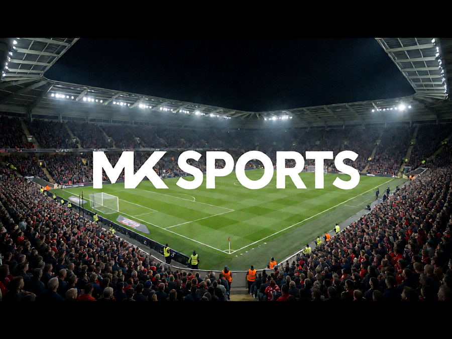 夜间灯光下的足球场全景，看台坐满观众，展示 MK SPORTS 赛事直播场景